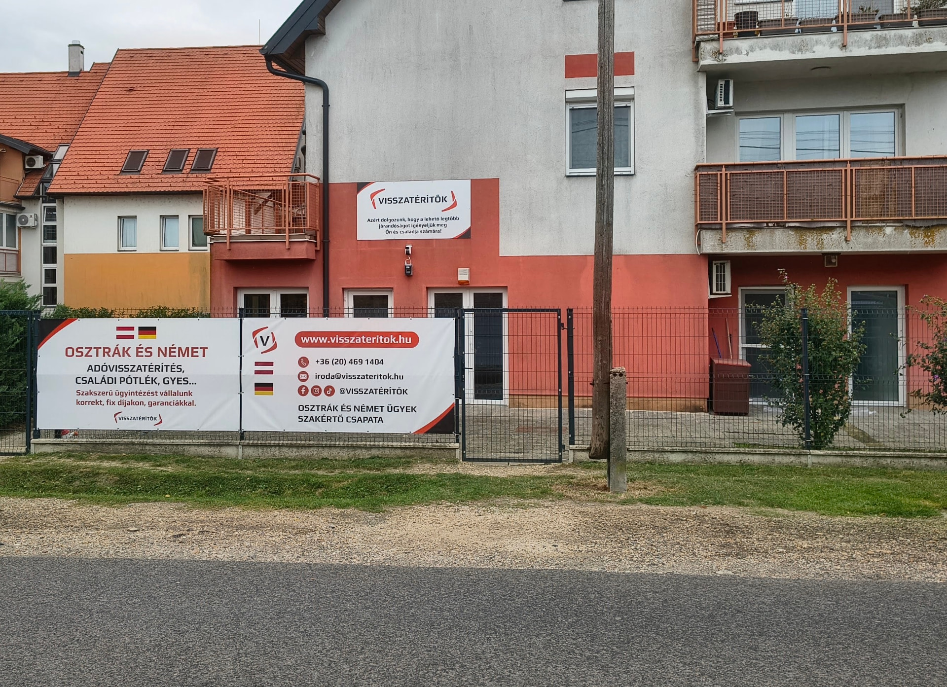 A Visszatérítők mosonmagyaróvári irodájának bejárata a Feketeerdei út felől, a cégtáblával és molinókkal
